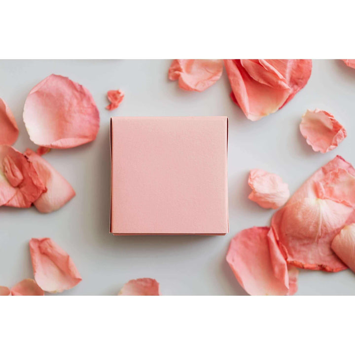 Boîte mensuelle rose entourée de pétales de fleurs pour produits naturels et artisanaux